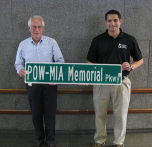 Pat Geer (left) and Mike Cassata hold the first POW-MIA Memorial parkway Sign